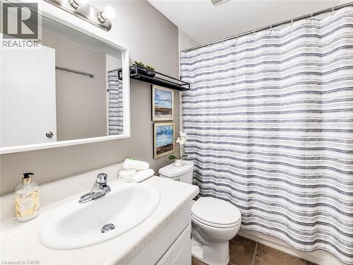 Bathroom featuring a white vanity with integrated sink, chrome faucet, white toilet, and tile flooring - 4 Avalon Place Unit# 303, Kitchener, ON 
