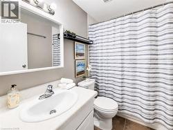 Bathroom featuring a white vanity with integrated sink, chrome faucet, white toilet, and tile flooring - 