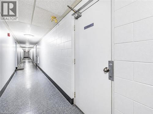 Long hallway with durable block walls, tile ceiling, and speckled flooring - 4 Avalon Place Unit# 303, Kitchener, ON 
