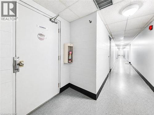 Extended hallway with durable flooring, acoustical tile ceiling, and overhead lighting - 4 Avalon Place Unit# 303, Kitchener, ON 