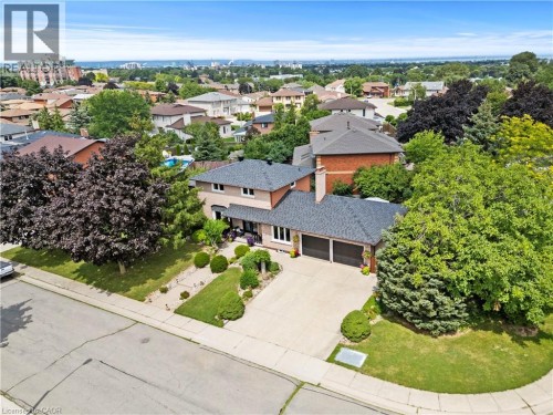Brick and stone exterior with modern architectural detailing, set on a landscaped lot featuring mature trees and manicured lawn - 87 Monte Drive, Hamilton, ON 