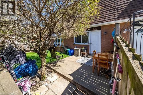 Brick exterior with a white entry door, number plaque, and a ground-level window - 648-654 Francis Road, Burlington, ON 