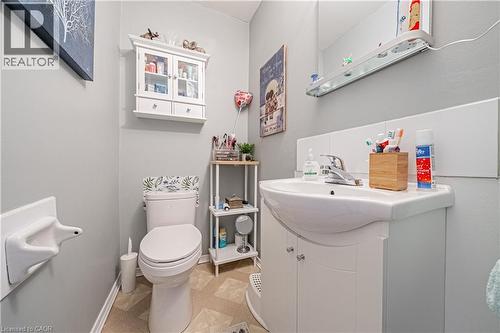 Bathroom featuring a white vanity with integrated sink, chrome faucet, white wall paneling, and light-toned geometric pattern flooring - 648-654 Francis Road, Burlington, ON 