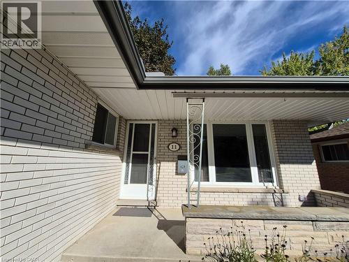 Exterior brick facade with contrasting dark gutters, white soffit, and a front entry door with a screen - 11 Duncairn Avenue, Kitchener, ON 