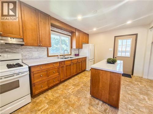 Kitchen featuring wood cabinetry, light-toned countertops, a tile backsplash, and an integrated sink - 11 Duncairn Avenue, Kitchener, ON 