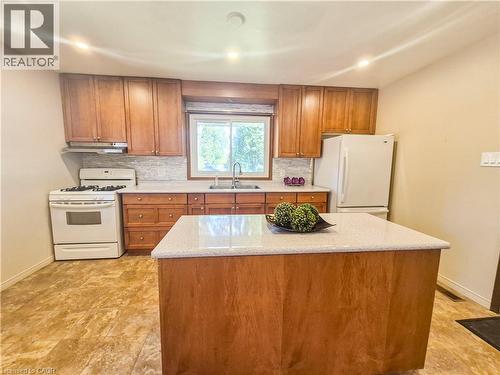 Kitchen featuring wood cabinetry, a center island with a light-toned countertop, a tile backsplash, and recessed lighting - 11 Duncairn Avenue, Kitchener, ON 