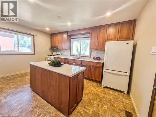 Kitchen featuring a central island with a light-toned countertop, wood-finish cabinetry, tile flooring, and recessed lighting - 11 Duncairn Avenue, Kitchener, ON 