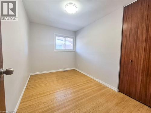 Hardwood flooring, wood-finish closet door, white walls, flush mount ceiling light, and a white window frame - 11 Duncairn Avenue, Kitchener, ON 
