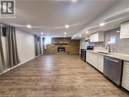 Spacious open concept room featuring wood-finish flooring, recessed lighting, and a stone-clad fireplace - 11 Duncairn Avenue, Kitchener, ON 