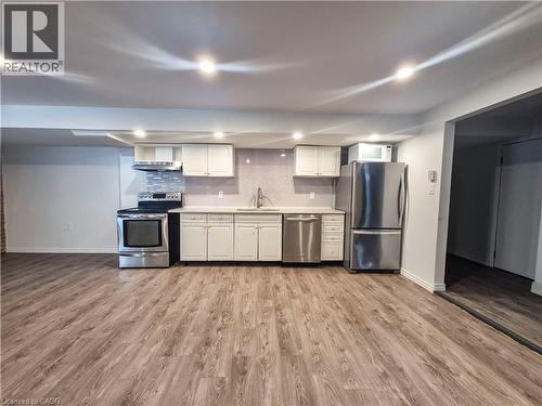 Open-concept kitchen with wood-finish flooring, white cabinetry, stainless steel appliances, and recessed lighting - 11 Duncairn Avenue, Kitchener, ON 