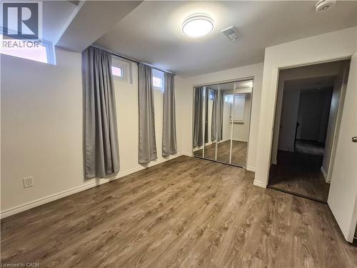 Wood-finish flooring throughout, complemented by a mirrored closet with sliding doors, and multiple windows - 11 Duncairn Avenue, Kitchener, ON 