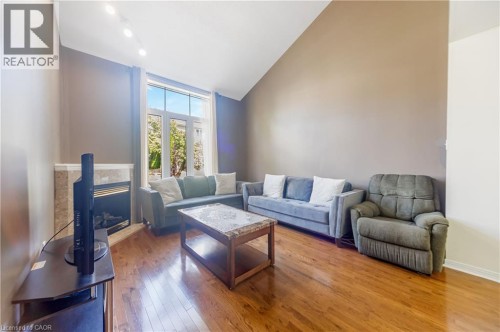 Bright living room featuring soaring vaulted ceilings with recessed lighting, warm wood-finish flooring, and large multi-pane windows allowing abundant natural light - 82 Milner Downs Crescent, Ottawa, ON 