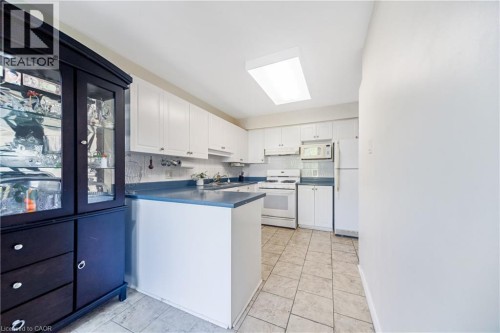 Kitchen featuring white cabinetry, a built-in microwave, a full-size refrigerator, and tile flooring - 82 Milner Downs Crescent, Ottawa, ON 
