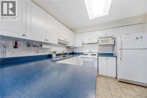Kitchen featuring white cabinetry, blue countertops, white tile backsplash, and a skylight - 82 Milner Downs Crescent, Ottawa, ON 
