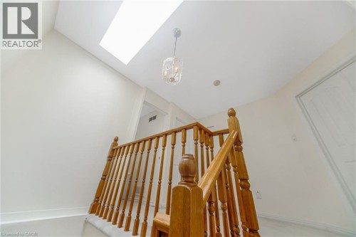 Skylight feature illuminating the stairway, wood banister with traditional spindles, and a decorative chandelier - 82 Milner Downs Crescent, Ottawa, ON 