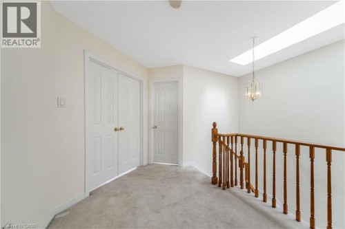 Wood-tone staircase railing with white spindles, skylight, and a decorative chandelier - 82 Milner Downs Crescent, Ottawa, ON 