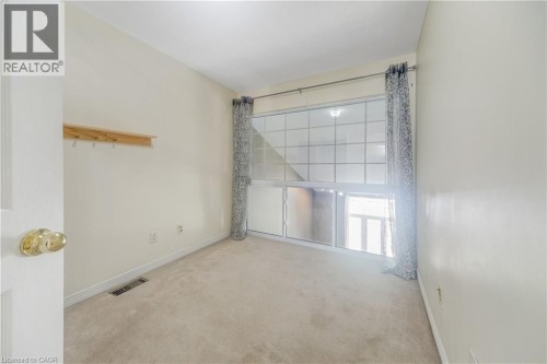 Carpeted interior with light-colored walls, a large multi-pane window, and a built-in wooden shelf with hooks - 82 Milner Downs Crescent, Ottawa, ON 