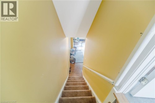Carpeted staircase with a white handrail and yellow walls - 82 Milner Downs Crescent, Ottawa, ON 