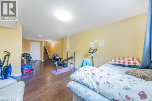 Spacious basement recreation area featuring wood-finish flooring, yellow-painted walls, recessed ceiling lighting, and ample room for multiple uses - 82 Milner Downs Crescent, Ottawa, ON 