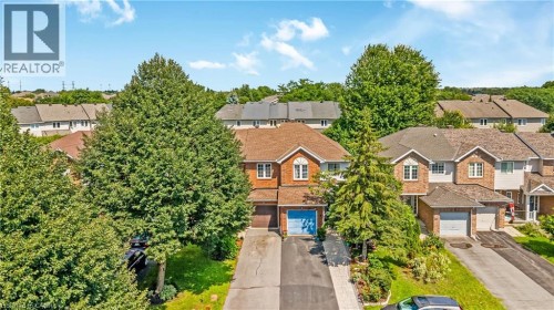 Brick exterior, dormer windows, attached garage, paved driveway, mature trees - 82 Milner Downs Crescent, Ottawa, ON 