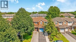 Brick exterior, dormer windows, attached garage, paved driveway, mature trees - 