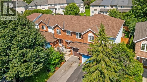 Red brick facade with arched windows, brown shingle roof, attached garage with blue door, and front porch with white railing - 82 Milner Downs Crescent, Ottawa, ON 