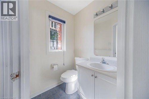 Vanity with integrated sink, rectangular wall mirror, three-light vanity bar, window with blinds, and tile flooring - 82 Milner Downs Crescent, Ottawa, ON 