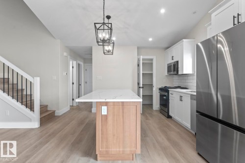 The property features a bright kitchen with white cabinetry, stainless steel appliances, and a central island with a white countertop - 807 Schooner Drive, Cold Lake, AB - Indoor Photo Showing Kitchen With Stainless Steel Kitchen