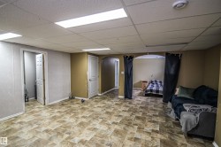 Finished basement with arched walkways, a paneled ceiling, and stone finish floors - 