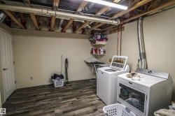 Laundry room with washer and clothes dryer and dark wood finished floors - 