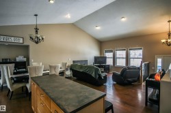Living room featuring a chandelier, vaulted ceiling, and dark wood-style flooring - 