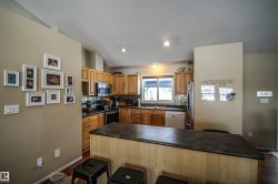 Kitchen featuring backsplash, a breakfast bar, dark countertops, vaulted ceiling, and stainless steel appliances - 