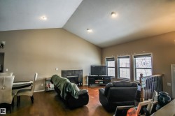 Living area with vaulted ceiling, dark wood-style floors, and a tiled fireplace - 