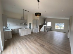 Kitchen with a chandelier, backsplash, a center island, light stone countertops, and modern cabinets - 