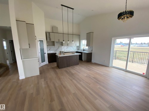 Kitchen with high vaulted ceiling, decorative light fixtures, a kitchen island, tasteful backsplash, and wood finished floors - 5421 60 Avenue, Vegreville, AB - Indoor