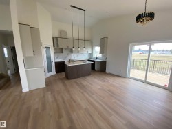 Kitchen with high vaulted ceiling, decorative light fixtures, a kitchen island, tasteful backsplash, and wood finished floors - 