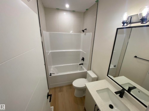 Bathroom featuring vanity, light wood-style floors, and washtub / shower combination - 5421 60 Avenue, Vegreville, AB - Indoor Photo Showing Bathroom