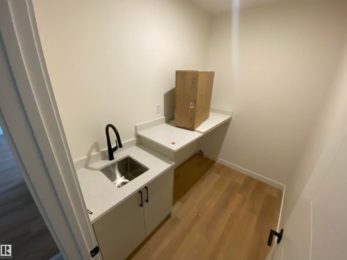 Laundry area with light wood-style floors and a sink - 5421 60 Avenue, Vegreville, AB - Indoor