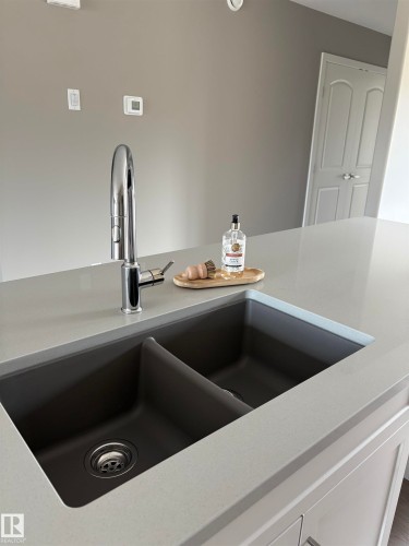 Kitchen view of light stone counters and white cabinetry - 7413 44 Avenue, Camrose, AB - Indoor Photo Showing Kitchen With Double Sink