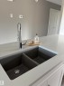 Kitchen view of light stone counters and white cabinetry - 7413 44 Avenue, Camrose, AB  - Indoor Photo Showing Kitchen With Double Sink 