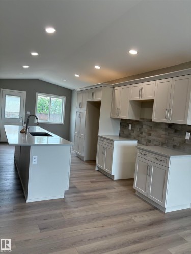 Kitchen featuring backsplash, white cabinets, light stone countertops, light wood finished floors, and recessed lighting - 7413 44 Avenue, Camrose, AB - Indoor Photo Showing Kitchen