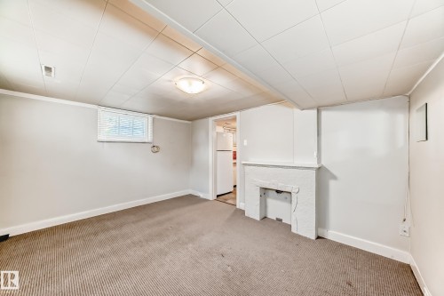 Below grade area with carpet floors and freestanding refrigerator - 12605 107 Avenue, Edmonton, AB - Indoor Photo Showing Other Room