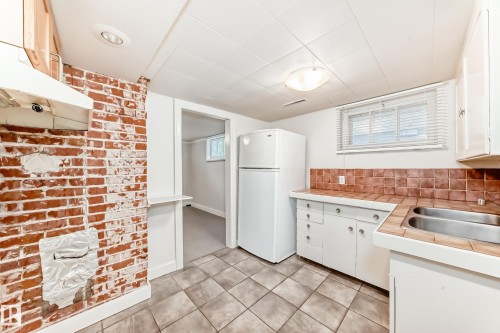 Kitchen featuring white cabinetry, freestanding refrigerator, under cabinet range hood, tile counters, and light tile patterned floors - 12605 107 Avenue, Edmonton, AB - Indoor Photo Showing Kitchen With Double Sink