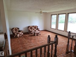 Living area with a textured ceiling, carpet floors, and ceiling fan - 