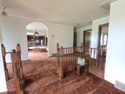 Hall featuring arched walkways, a textured ceiling, carpet, and an upstairs landing - 