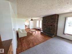 Carpeted living area featuring healthy amount of natural light, arched walkways, a fireplace, and a textured ceiling - 