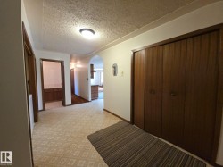 Corridor featuring arched walkways, a textured ceiling, and light carpet - 