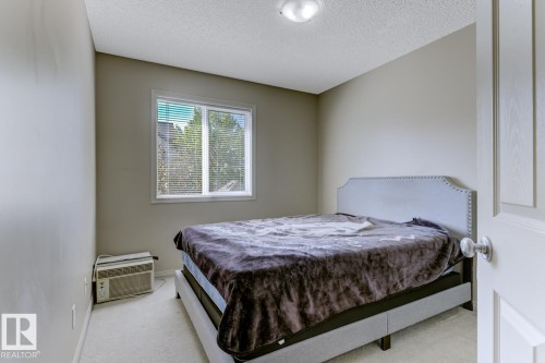 Carpeted bedroom with a textured ceiling and a wall mounted AC - 18 5281 Terwillegar Boulevard, Edmonton, AB - Indoor Photo Showing Bedroom