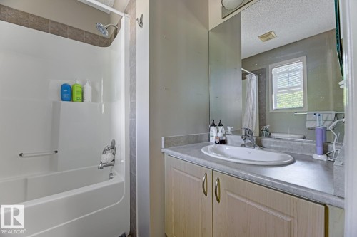 Full bathroom with a textured ceiling, vanity, and shower / tub combo with curtain - 18 5281 Terwillegar Boulevard, Edmonton, AB - Indoor Photo Showing Bathroom