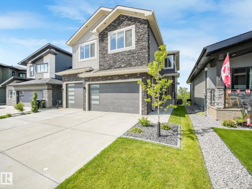 View of front of house featuring stone siding, a garage, board and batten siding, concrete driveway, and a front yard - 15 Elwyck Gate, Spruce Grove, AB - Outdoor With Facade